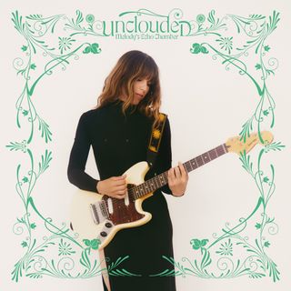 Woman in a black dress holding a cream Fender Mustang guitar, framed by a green Art Nouveau floral border on a white background.
