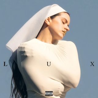 Woman in a white nun's habit and form-fitting white top, eyes closed, against a pale blue sky.