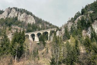 A two story train viaduct from below surrounded by trees and rock walls